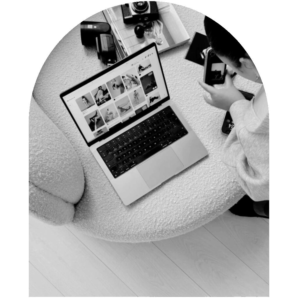 Laptop displaying visual content while a person photographs it with a camera in a creative workspace.