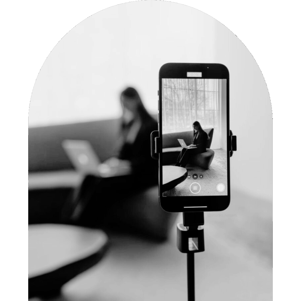 Social media content being recorded on a smartphone while a professional works on a laptop